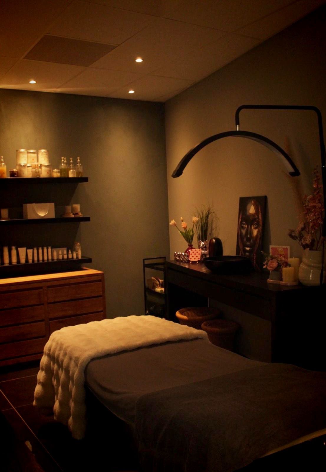 De behandelruimte met behandelbed, productplanken en een halvemaanlamp
