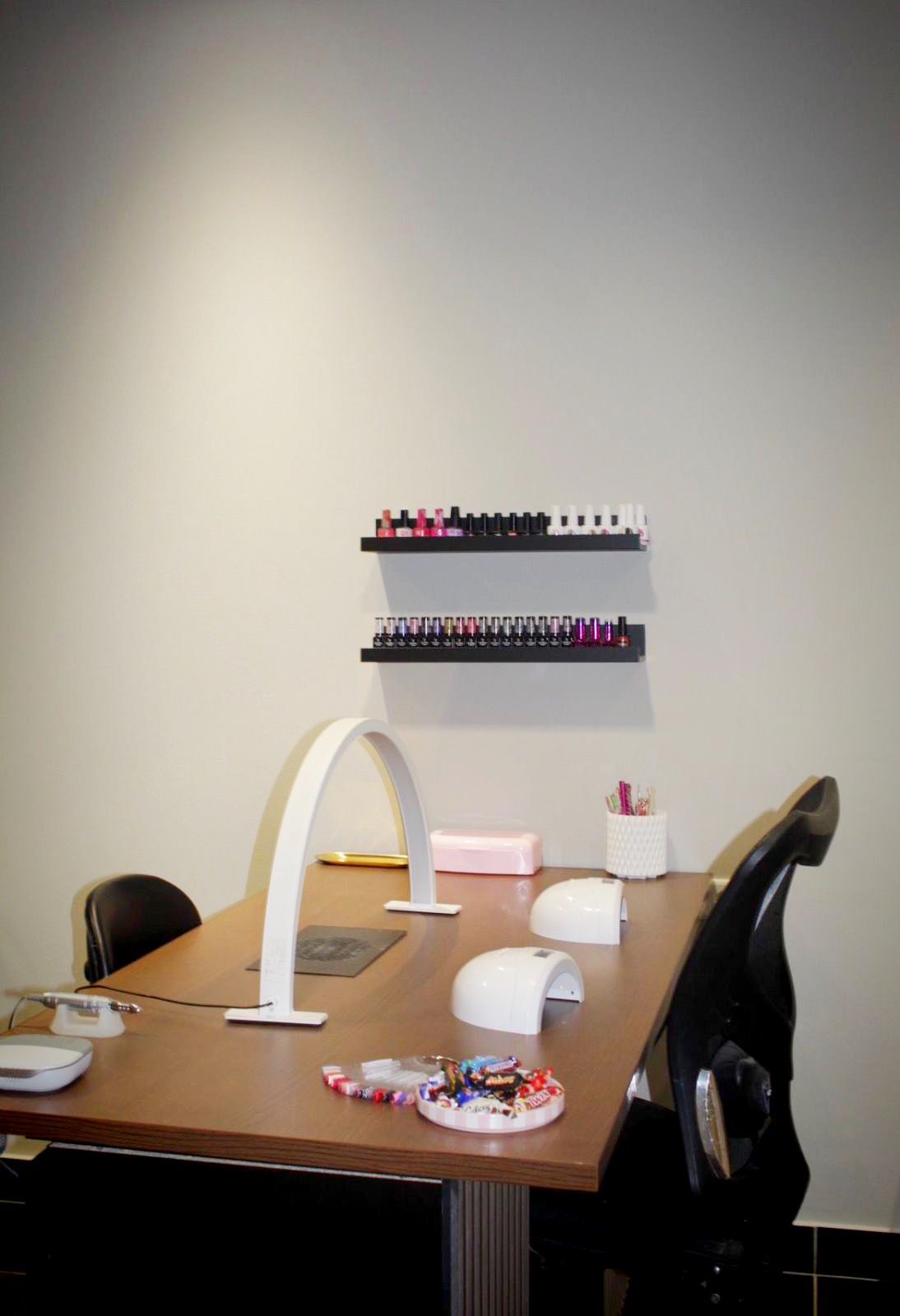 De nageltafel met witte booglamp, twee LED-lampen en het rek met gellakkleuren