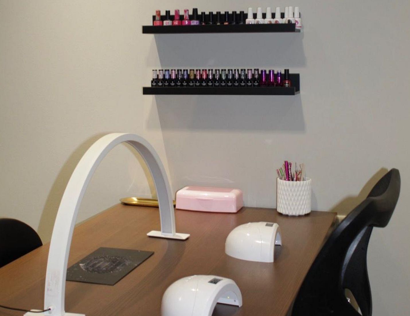 De nageltafel vanaf de zijkant, met booglamp, roze LED-lamp en het lakrek